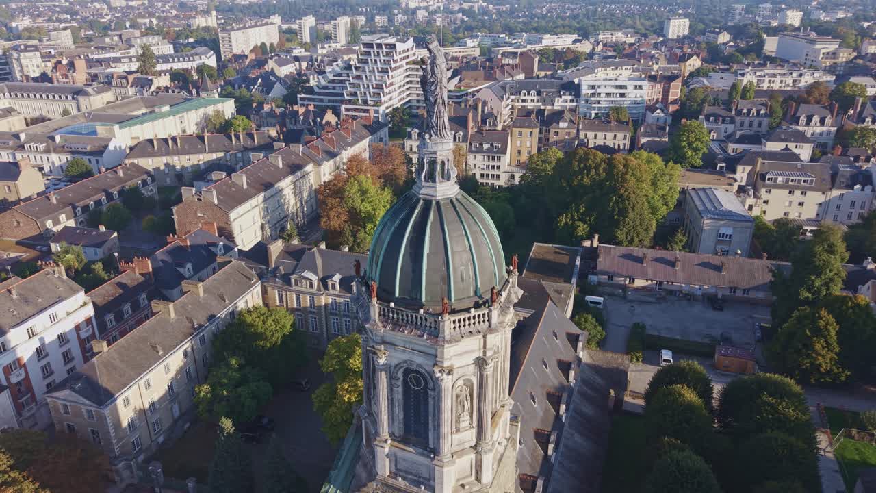 Drone panning then orbiting around Saint-Melaine tower above Rennes at sunrise