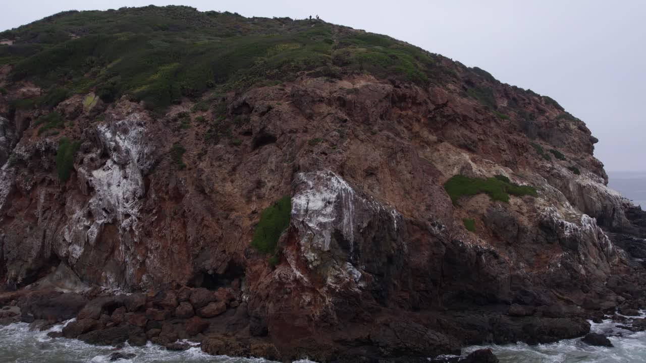 una amplia vista aérea de la escarpada costa de malibu, california, que muestra los acantilados naturales y el paisaje verde contra el fondo del océano pacífico.