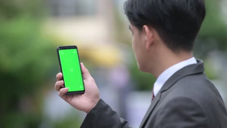 young handsome asian businessman showing phone in the streets outdoors