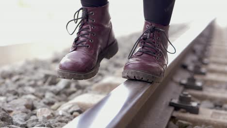 young woman with purple boots walks on the train track