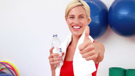 mujer rubia bebiendo agua con los pulgares hacia arriba