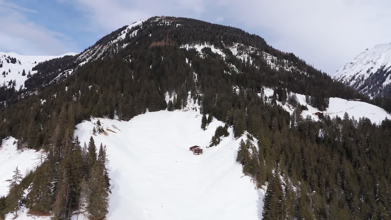 Snowy mountain landscape with evergreen trees and a lone cabin in Langwies, Switzerland