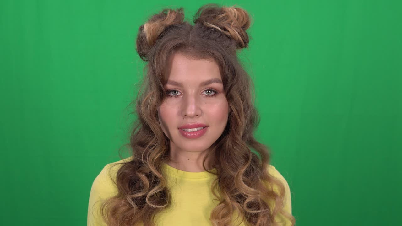 красивая молодая девушка с положением позирует с апельсинами и улыбается, глядя в камеру на желтом фоне