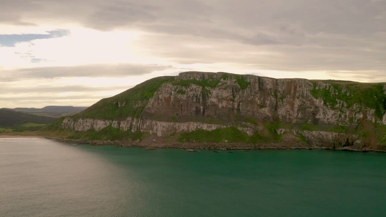 tiro lento en órbita de derecha a izquierda de los acantilados a lo largo de la costa en nueva zelanda durante la puesta de sol