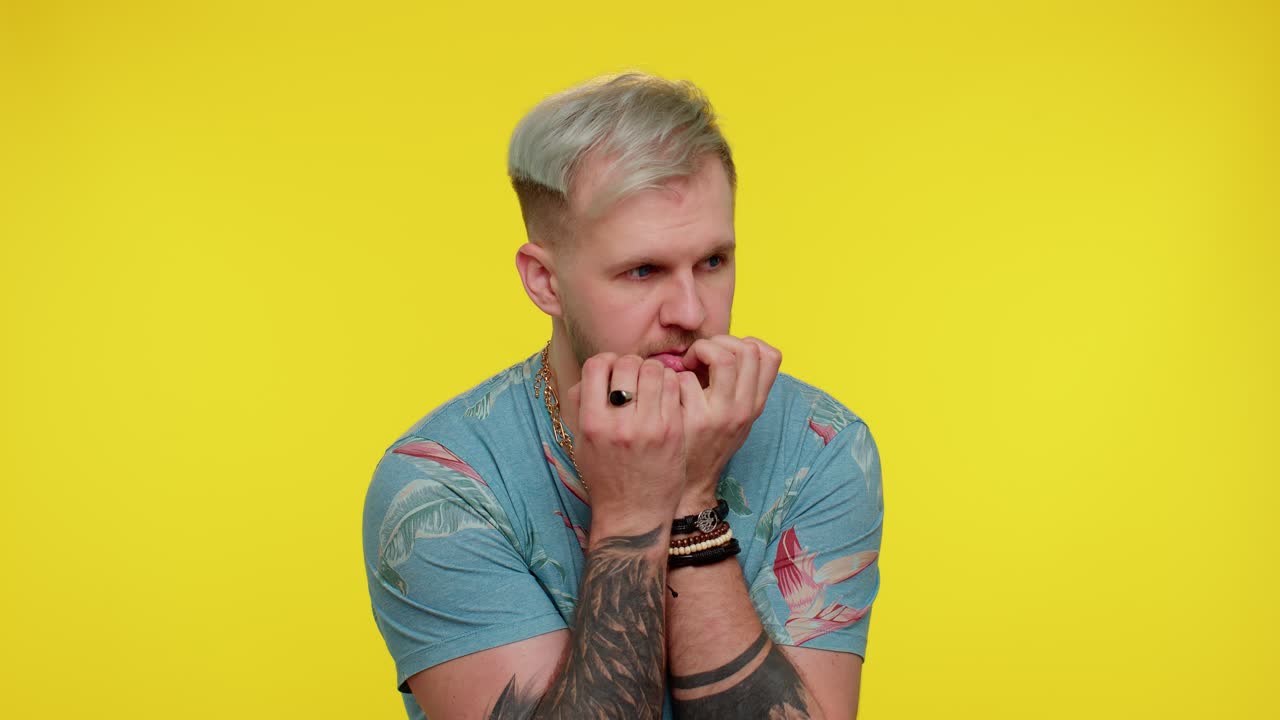 Young scared man biting nails, feeling worried nervous about serious troubles, stress and anxiety