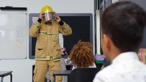 frontansicht kaukasischer männlicher feuerwehrmann unterrichtet schulkinder über brandsicherheit im klassenzimmer 4k