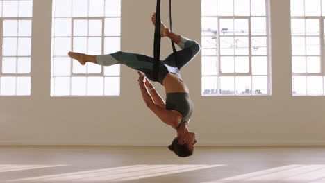 aerial yoga woman practicing bound one-legged king pigeon pose hanging upside down using hammock enjoying healthy fitness lifestyle exercising in studio training meditation at sunrise