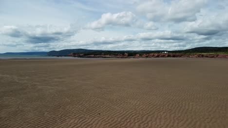 low flying drone shot over waterside beach heading towards bay of fundy, new brunswick