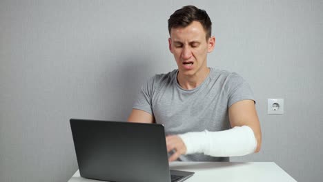 Brunet man works distantly feeling pain in broken forearm