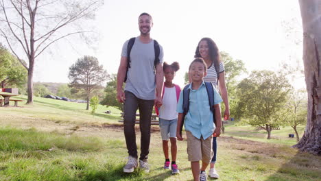 family wearing backpacks hiking in countryside together