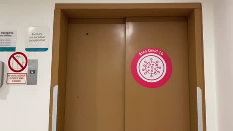 covid area red warning sticker in elevator front door in clinic - hospital - latin america