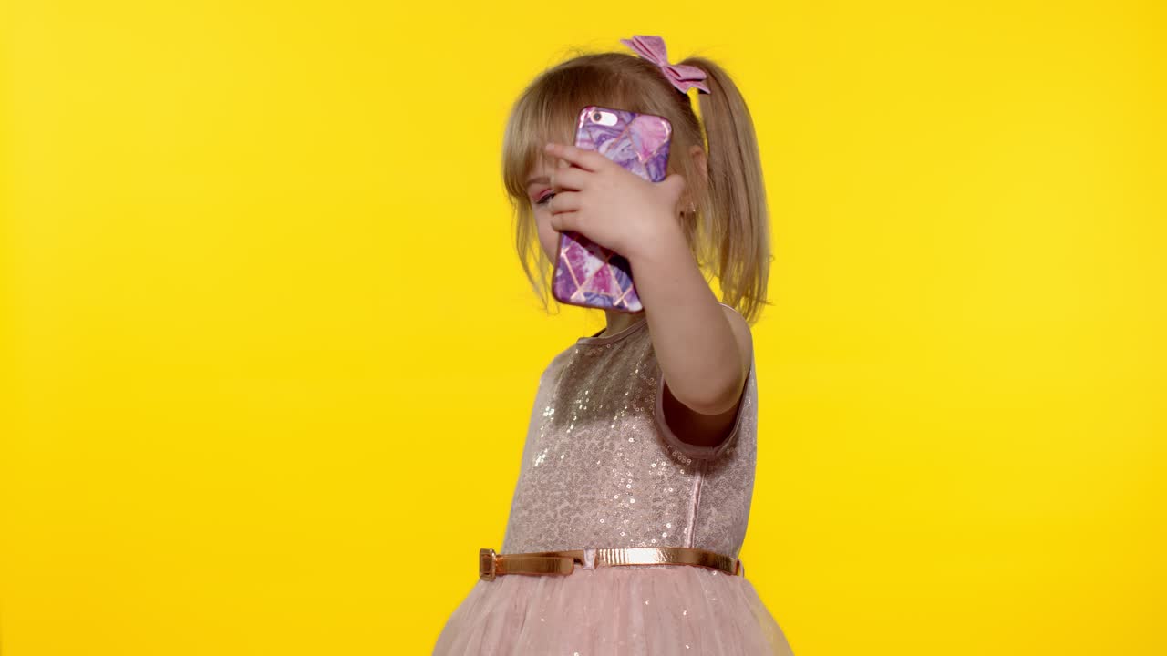 niña usando un teléfono inteligente. retrato de un niño rubio que emocionalmente se hace una selfie en el teléfono móvil