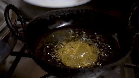 bubbling hot oil with guror handesh cooking underneath in small pan