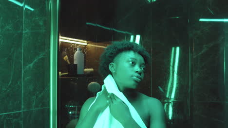 mujer afroamericana usando una toalla después de la ducha en el baño