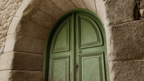 an old green wooden door set in a stone archway