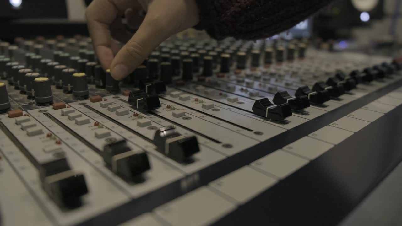 Audio sound mixer console in recording studio. fingers moving the sliders and turning the knobs