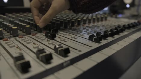 audio sound mixer console in recording studio. fingers moving the sliders and turning the knobs