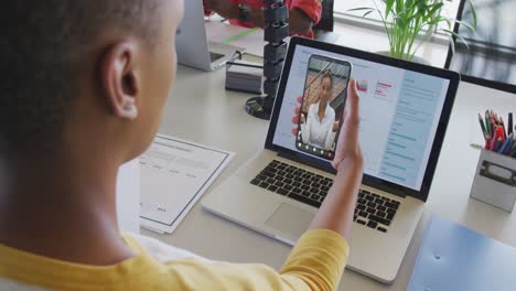 mujer de negocios afroamericana que usa un teléfono inteligente para una videollamada con un colega de negocios