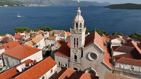 drone orbit of chapel overlooking ocean korcula old town terracotta roofs and harbor, surrounded by the adriatic sea, saint mark's cathedral