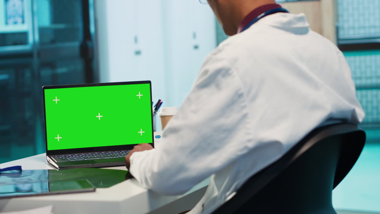 Doctor working on laptop with green screen
