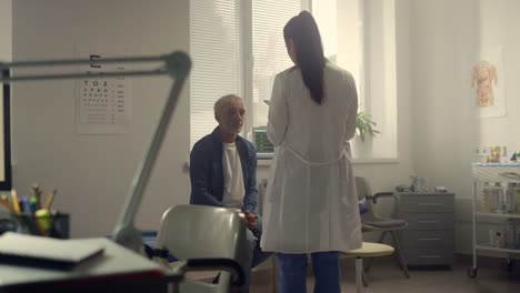 woman doctor conducting health examination senior patient in hospital office.