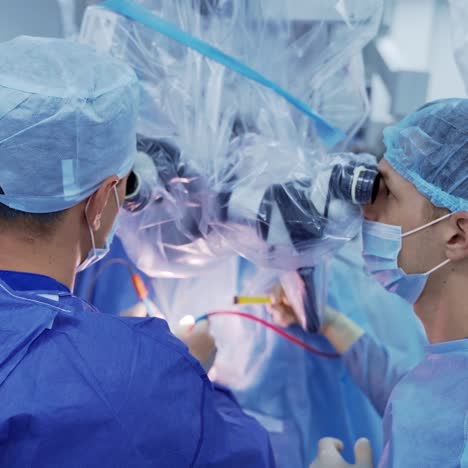 surgical procedure with medical microscope. doctors in medical uniform and masks looking through the microscope while operate patient in modern hospital.