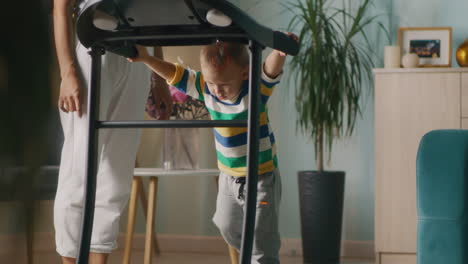 toddler learning to walk on a treadmill with mother's assistance