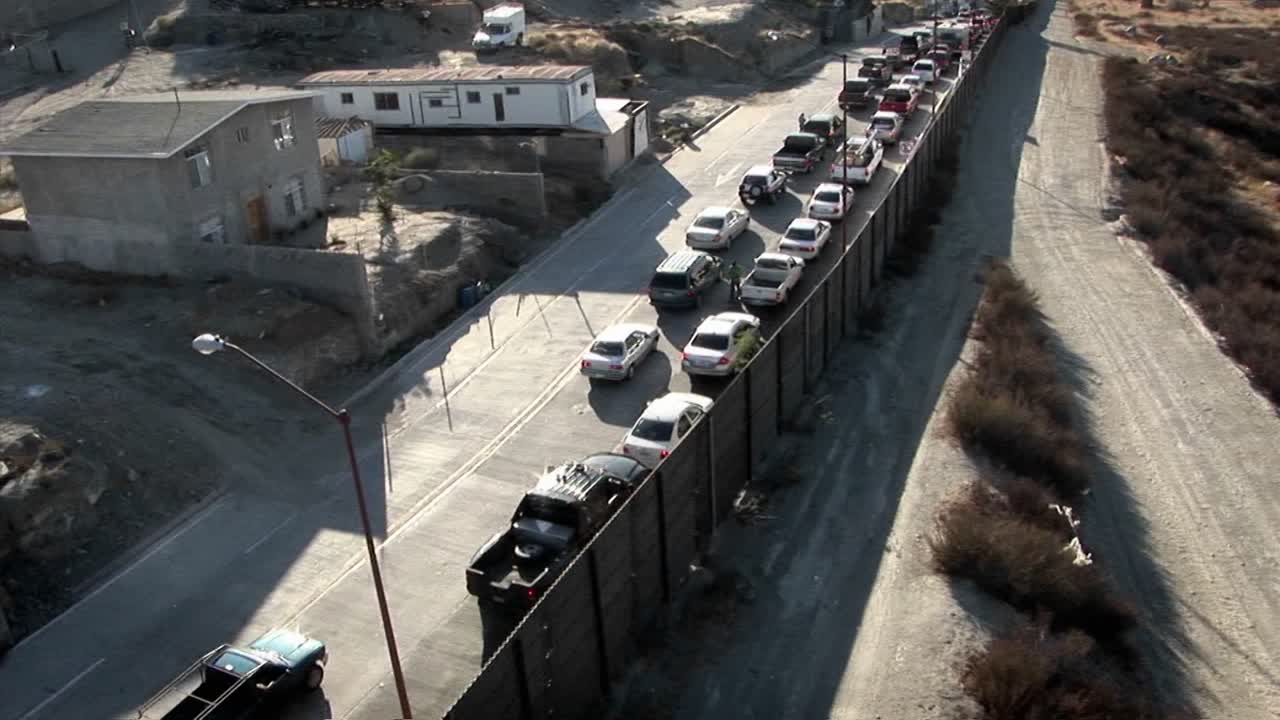 자동차는 높은 울타리를 따라 두 줄로 늘어서 있습니다.