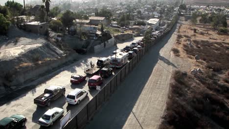 Cars-are-lined-up-in-two-rows-along-a-tall-fence