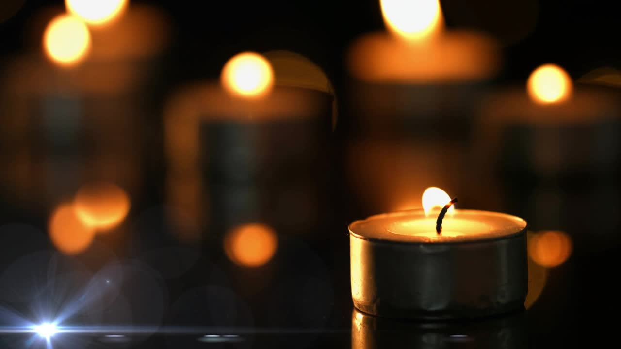 Lens flare appearing sweeping across amber bokeh as candle flame flickering on table warming scene