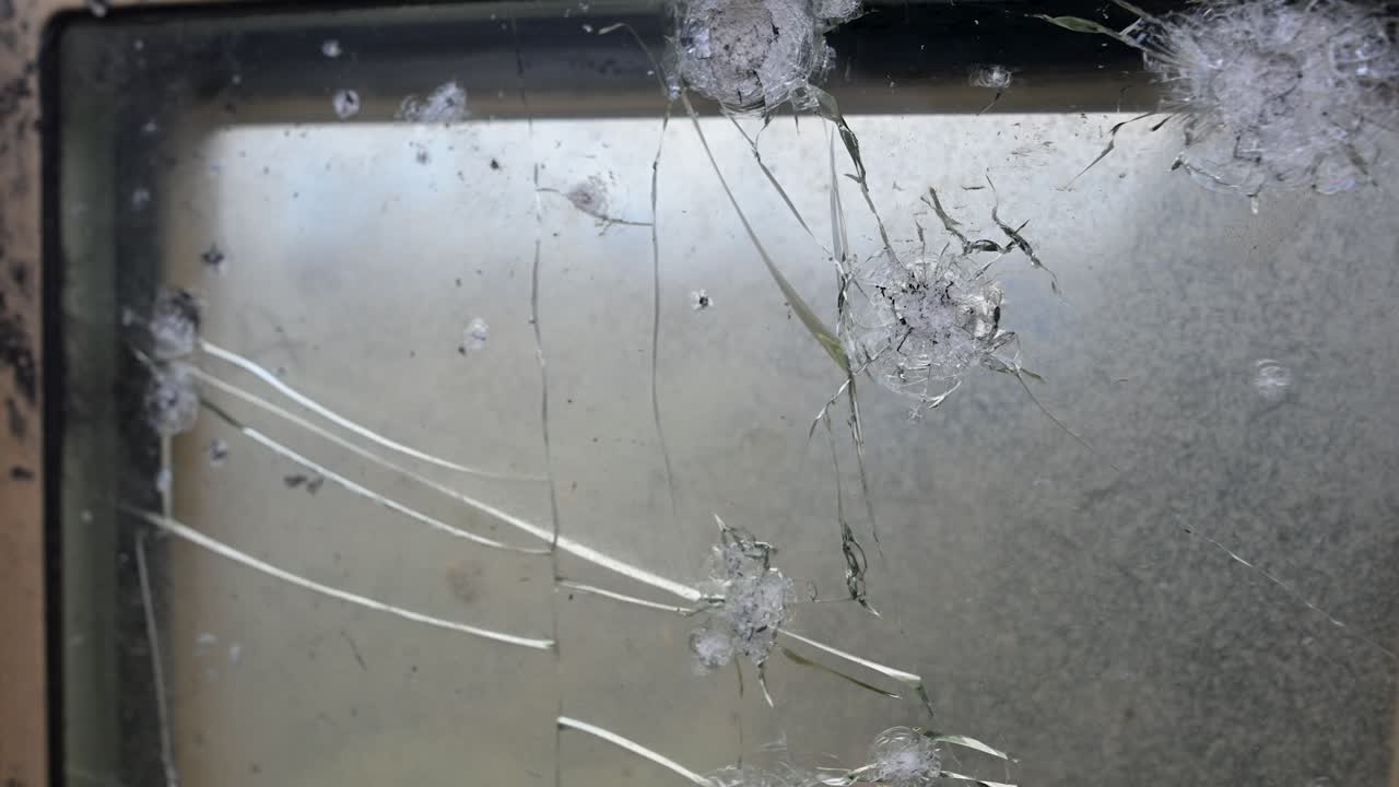 The scars of combat seen from inside an M2 Bradley. This POV shot looks through a damaged ballistic shield as the vehicle operates near the frontline in Ukraine