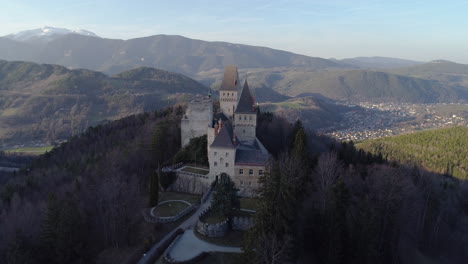 tiro de dron ascendente de un castillo en una colina con montañas en el fondo, 4k uhd