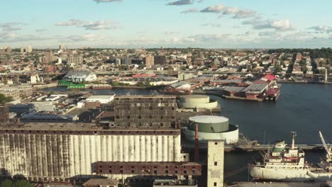 Toma-Aérea-Estacionaria-De-La-Enorme-Terminal-De-Granos-Abandonada-Y-Un-Barco-Oxidado-Cercano-En-Brooklyn,-Nueva-York