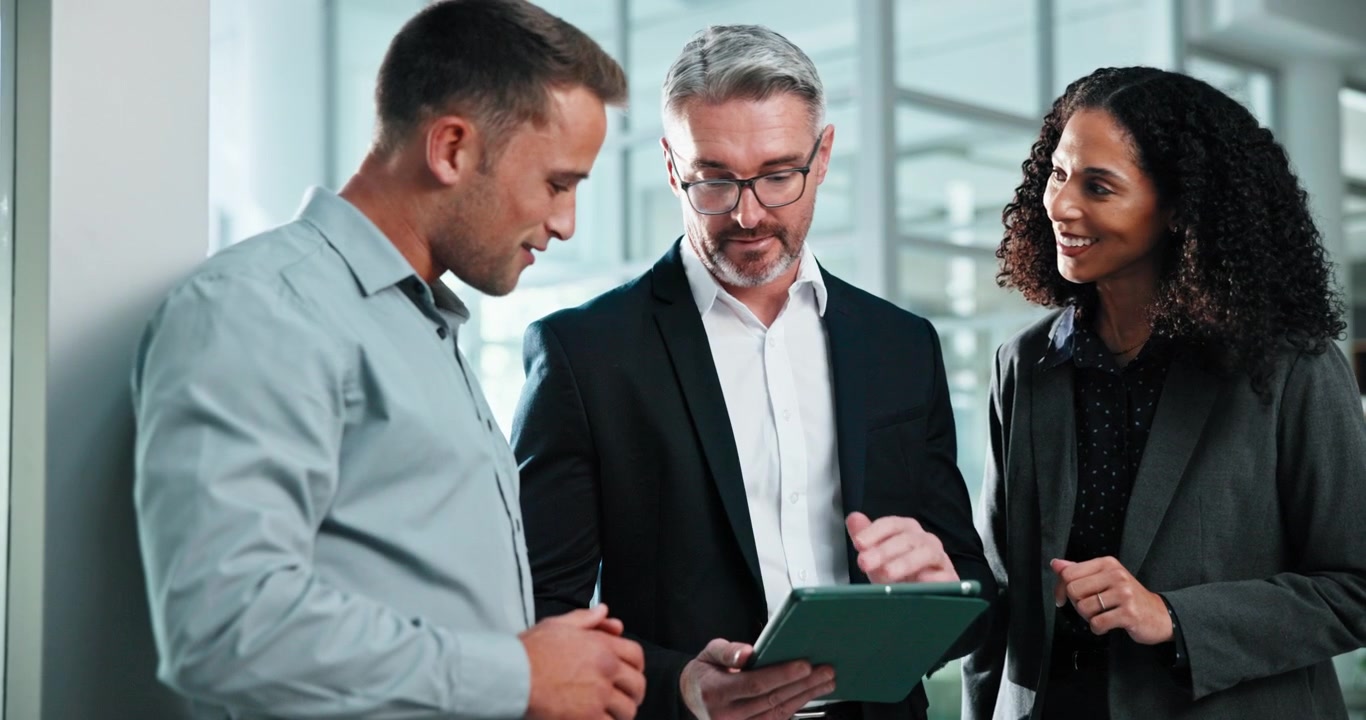 Business Professionals Discussing Strategy on a Tablet in an Office