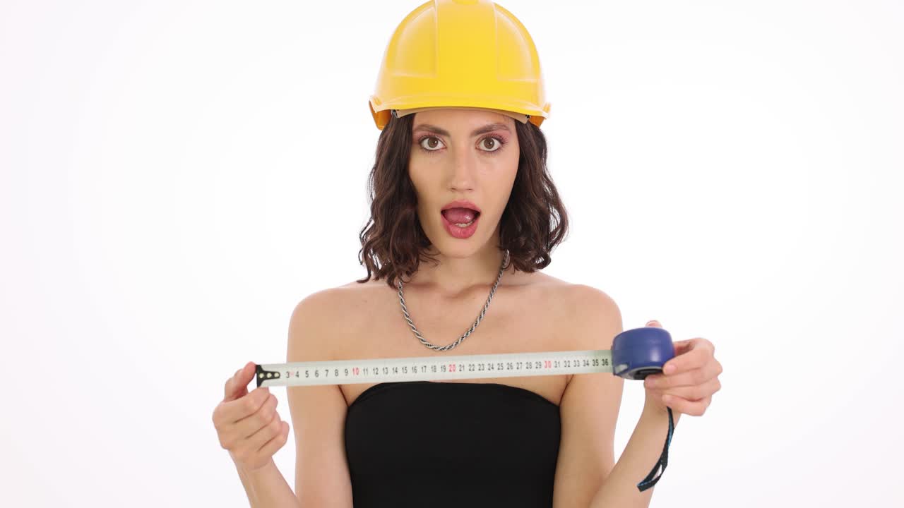 Woman in a hard hat with a measuring tape showing surprised expressions