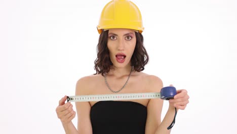 woman in a hard hat with a measuring tape showing surprised expressions