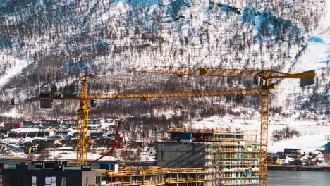 Zeitraffer-Von-Der-Baustelle-Mit-Riesigen-Kränen,-Die-Material-Auf-Die-Spitze-Eines-Gebäudes-Heben,-Und-Vielen-Menschen-Bei-Der-Arbeit,-Aufgenommen-Im-Winter