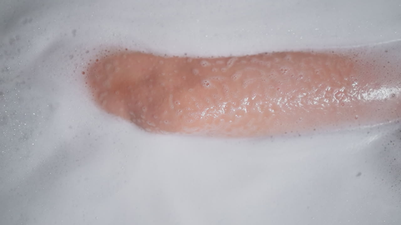 женщина в пенной воде ванны вблизи. элегантная леди принимает расслабляющую ванну с продуктами по уходу за кожей дома. молодая женщина наслаждается рутиной ухода за телом