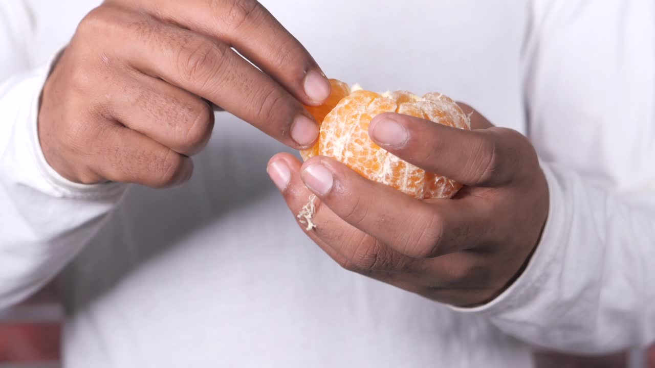persona pelando y comiendo una naranja mandarina