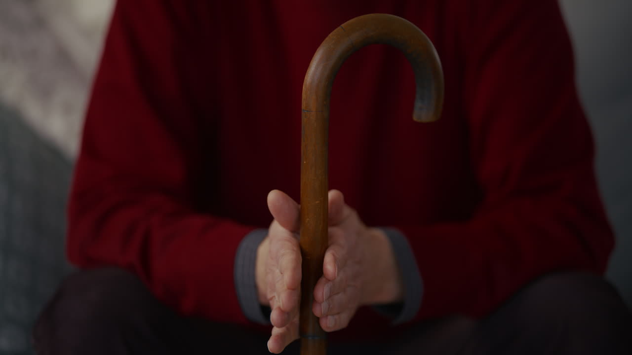 Primo piano delle mani di una persona anziana che impugnano un bastone di legno