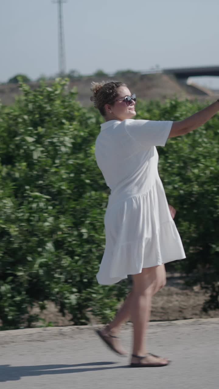 Woman in white dress taking a selfie outdoors