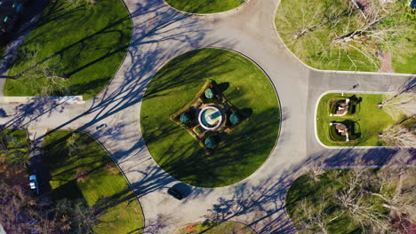 symmetrical aerial view of roundabout with cars driving around the park