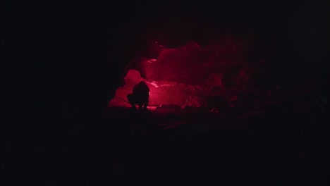 person exploring a dark cave at night with red light