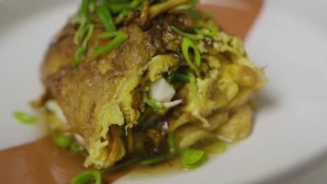 Close-up-on-abalone-and-egg-dish,-decorated-with-greens-on-top