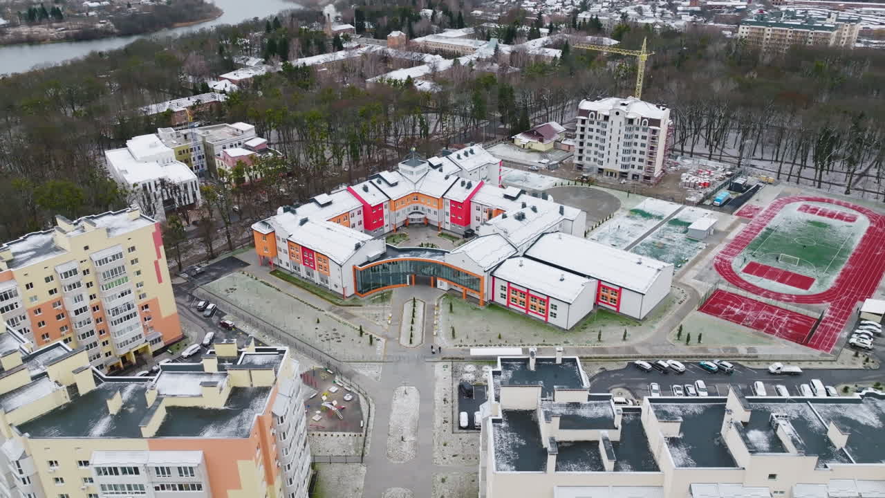New unusual building of a city school. Creative bright design of a school building in a new residential district. Cityscape and river at the background.