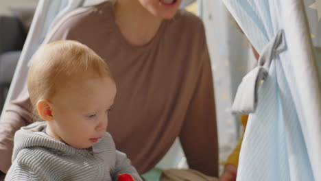 mother playing with kids in teepee tent