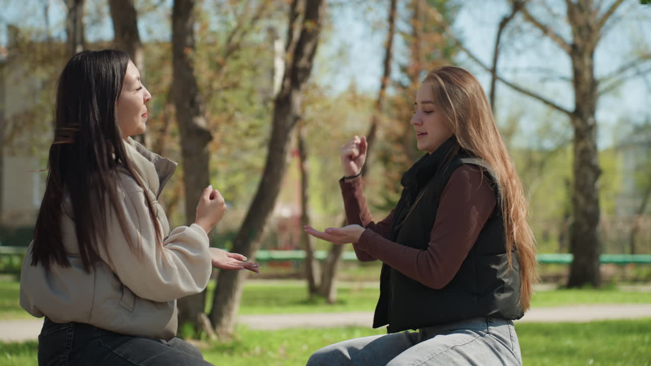 두 친구가 편안하게 수신호를 보내고, 친구들이 야외에서 비공식적인 손짓 콘테스트에 참여하고, 두 친구가 캐주얼 모임에서 편안한 수신호 경쟁에 참여합니다.