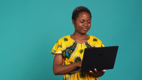 Thoughtful-woman-browsing-websites-on-a-laptop-in-studio