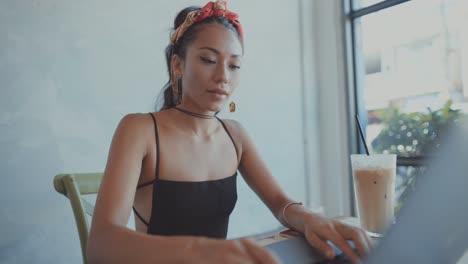 mujer trabajando en una computadora portátil en un café