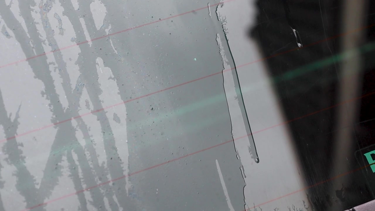 Video of water running down the back windshield of a car.